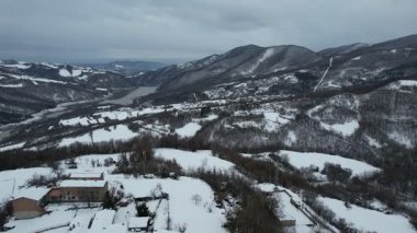 İtalya, Piacenza, Morfasso 'daki Vezzolacca köyünün havadan görünüşü, el değmemiş kış karıyla örtülmüş, kilise kulesiyle kaplı.