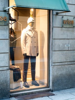 Cremona, İtalya - 24 Aralık 2025 Modern giyimli şık bir manken bir mağazanın vitrininde durup, yoldan geçenleri son moda eğilimlerini keşfetmeye davet ediyor..