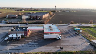 Kırsal bir benzin istasyonunda kırmızı ve beyaz çatılı bir kamyonun hava görüntüsü.