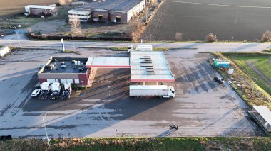 Büyük bir otoparkı olan bir kamyon durağında yakıt ikmali yapan bir kamyonun hava görüntüsü.