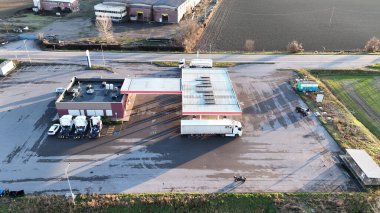 Büyük bir otoparkı olan bir kamyon durağında yakıt ikmali yapan bir kamyonun hava görüntüsü.