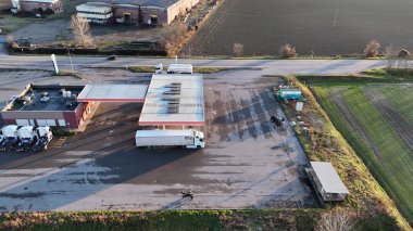 Kırsal bir benzin istasyonunda kırmızı ve beyaz çatılı bir kamyonun hava görüntüsü.