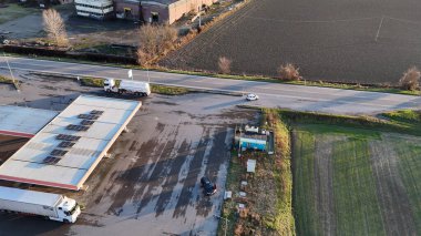 Strada Statale Padana Inferiore SS 10 benzin istasyonu ve kamyon durağı Piacenza, İtalya 'da altın bir günbatımının altında verimli tarım sahalarına kurulmuş ve kırsal altyapı sergilenmektedir.