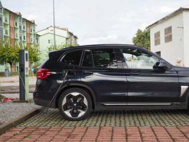 Crema, İtalya - 5 Temmuz 2025 Şık siyah bir BMW elektrikli SUV modern bir şehirde çevre dostu ulaşım sergiliyor..