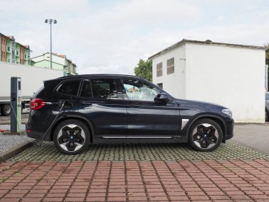 Crema, İtalya - 5 Temmuz 2025 Şık siyah bir BMW SUV modern bir elektrikli araç istasyonunda şehir ortamında, çevre dostu ulaşım ve daha temiz bir araç için sürdürülebilir teknoloji sergiliyor