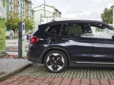 Crema, İtalya - 5 Temmuz 2025 Modern bir şehir istasyonunda parlak siyah bir BMW elektrikli araba, sürdürülebilir ulaşım ve günlük hayatta çevre dostu teknoloji sergiliyor.