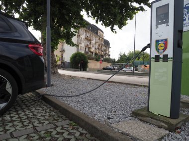 Crema, İtalya - 5 Temmuz 2025 Modern bir şehir şarj istasyonunda elektrikli araba şarj ediliyor. Sahne, sürdürülebilir yaşam ve çevre dostu ulaşımı tasvir ediyor.