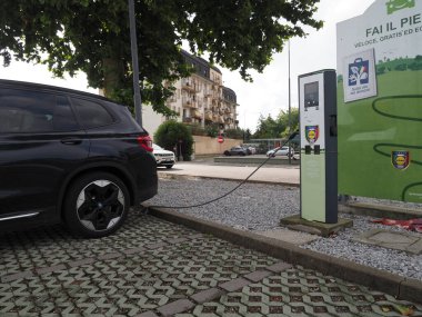 Crema, İtalya - 5 Temmuz 2025 Şık siyah bir BMW SUV kentsel bir ortamda, çevre dostu ulaşım ve sürdürülebilir şehirde modern bir elektrikli araç istasyonunda şarj oluyor.