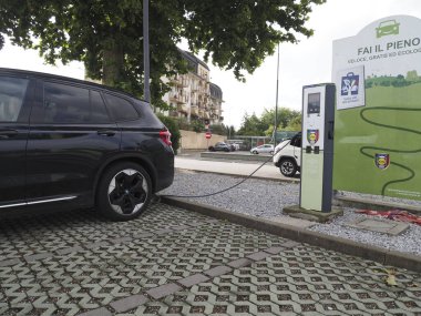 Crema, İtalya - 5 Temmuz 2025 Modern bir şehir şarj istasyonunda elektrikli bir araç şarj ediliyor, sürdürülebilir ulaşım ve çevre dostu teknoloji sergileniyor.