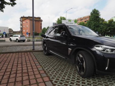 Crema, İtalya - 5 Temmuz 2025 Şık siyah bir BMW SUV, modern bir şehir ortamında sürdürülebilir ulaşım sergiliyor. Sahne, çevre dostu