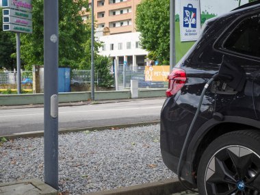 Crema, İtalya - 5 Temmuz 2025 Modern bir şehir şarj istasyonunda parlak siyah bir BMW elektrikli araba, sürdürülebilir ulaşım ve çevre dostu teknoloji sergiliyor.