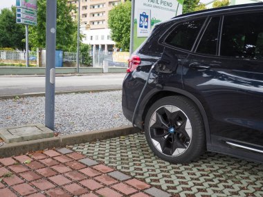 Crema, İtalya - 5 Temmuz 2025 Çağdaş bir şehirde çevre dostu ulaşım ve yenilikçi teknoloji sergilenen modern bir şehir istasyonunda parlak siyah bir BMW elektrikli SUV şarjı.