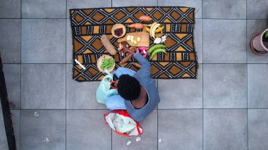 Bir insan taze sebzelerle çevrili oturur. Geleneksel bir Batı Afrika yemeği pişirmeye hazır muz, tatlı patates ve yer elması da dahil.