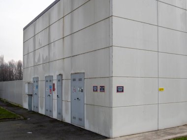 Cremona, İtalya 8 Ocak 2026 İtalya 'da Cremona, İtalya' da çok sayıda gri metal kapı ve beton panelinde çeşitli uyarı levhaları bulunan katı, modern endüstriyel yapı cephesi