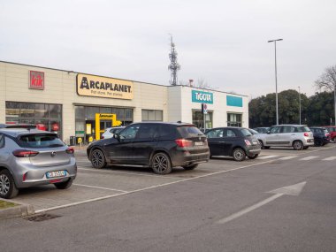 Cremona, İtalya 8 Ocak 2026. Cremona, Lombardy, İtalya 'da yer alan Arcaplanla ve Tigota gibi çeşitli perakende mağazalarının önünde park halindeki araçlar.