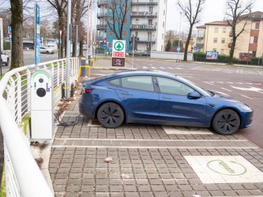 Cremona, İtalya 9 Ocak 2026 Tesla Model 3 Highland elektrikli otomobili sürdürülebilir taşımacılığı temsil eden Eurospar park alanındaki özel bir istasyonda şarj ediliyor