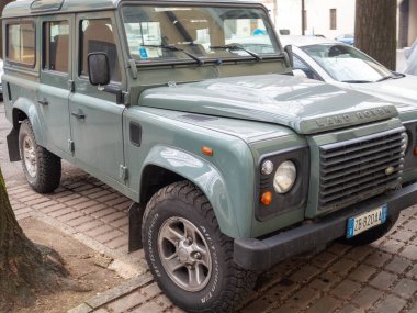 Cremona, İtalya 9 Ocak 2026 Land Rover Defender 110 TD5 Keswick Green 'de kaldırım taşlarının üzerine park edilmiş, engebeli şehir keşfi ve off-road macerasına hazır.
