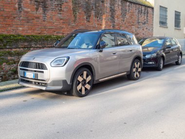 Cremona, İtalya 9 Ocak 2026 Mini Yurttaş SE ALL4 elektrikli SUV Eriyen Gümüş III 'te siyah çatılı tuğla duvar ve kapı kenar manzaralı, kentsel ayarlı