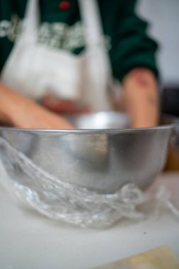 Önlüklü bir kadın mutfakta klasik bir İtalyan yemeği için taze, otantik malzemeler kullanarak özenle el yapımı tortelli makarna hazırlamakla meşgul.