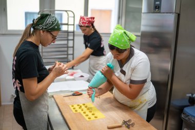 Üç bandanalı ve önlüklü kadın titizlikle Tortelli 'yi beceriyor. Klasik İtalyan makarnası. Taze, yerel malzemeler ve mutfak aletleri kullanıyor.