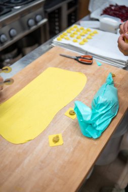 Şef, geleneksel tortelli makarnayı ustaca elleriyle hazırlıyor. Toskana 'daki bir İtalyan profesyonel mutfağında taze sarı hamuru yerel malzemelerle doldurmak. El yapımı mutfak sanatı oluşturuluyor