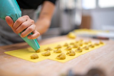 Taze makarna hamurunun içine dikkatlice doldurup tortelli oluşturan bir insanın ellerinin yakın plan çekimi.