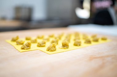 Tortelli 'ye dönüşmeye hazır sarı hamur tabakalarına yerleştirilmiş küçük porsiyonlar.