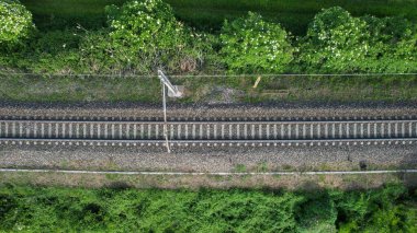 Bir insansız hava aracı Po Vadisi 'ndeki ağaçların ve otların arasından geçen paralel tren raylarını yakalıyor.