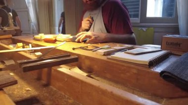 Cremona, İtalya - 18 Şubat 2022 Yetenekli bir sanatçı, İtalyan lutherie 'sinde özel ekipman ve malzemeler ile çevrili bir müzik aleti için ahşap şekillendirmek için el aletleri kullanır