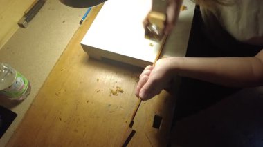 Keman yayı üzerinde titizlikle çalışan, geleneksel zanaatkarlığı ve detaylara olan bağlılığını gösteren bir kişinin yakın çekimi.