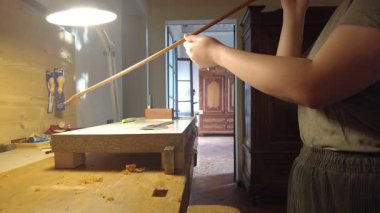 Bir zanaatkar ahşap yay üzerinde titizlikle çalışır ve geleneksel marangozluk becerilerini gösterir.