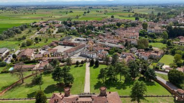 Procaccini Şatosu mimarisi görkemli bir şekilde yemyeşil tarım tarlalarının ve İtalya 'nın Pavia kentindeki Chignolo Po köyünün ortasında duruyor. Uçsuz bucaksız mavi gökyüzünün altında beyaz bulutlar var.
