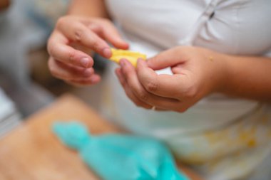 Mutfak hazırlıkları için sarı hamuru dikkatlice şekillendiren eller.