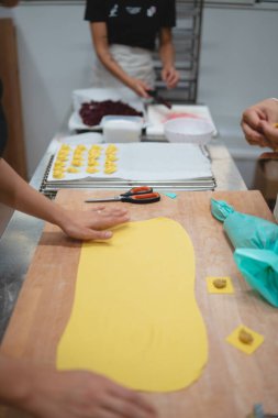 Tahta üzerinde taze makarna hamuru şekillendiren eller, doldurulmuş mantı hazırlayan eller.
