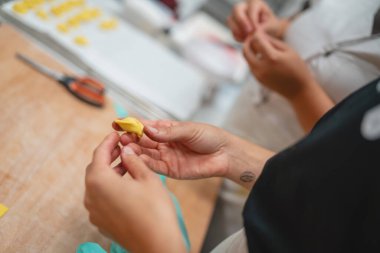 Yakın plan çekimde taze makarna hamurunu narin tortellini şeklinde dikkatlice şekillendiriyorum.