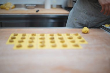 Taze ev yapımı ravioli profesyonel bir mutfakta ahşap bir masada hazırlanıyor.