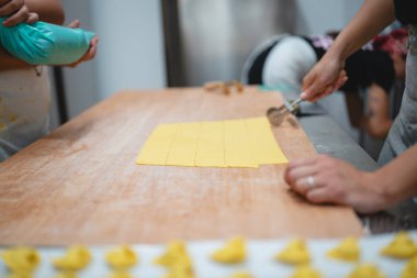 Ravioli hazırlığı için ev yapımı makarna hamuru kare şeklinde kesiliyor.