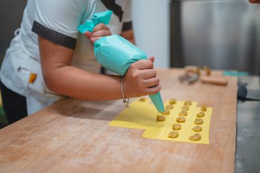 Şef dikkatli bir şekilde ev yapımı ravioli için makarna hamuru dolduruyor.