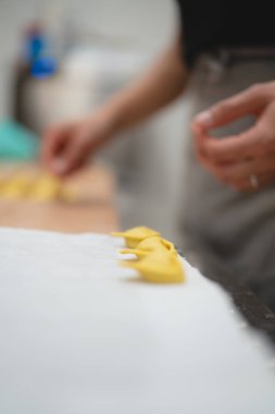 Taze yapılmış tortellini makarna hamuru mutfakta elle şekillendiriliyor.