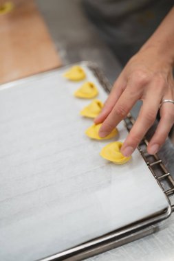 Parşömen kağıdıyla kaplı fırın tepsisi üzerinde el yapımı taze tortellini makarna.