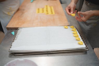 Ev yapımı tortellini makarna dikkatlice şekillendiriliyor ve soğutma rafında diziliyor.