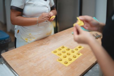 Eller dikkatlice mutfaktaki ahşap bir tahtada taze ravioli makarna yapıyor.