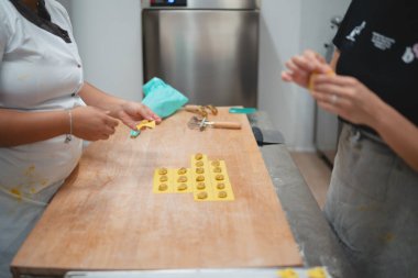 İki şef, profesyonel bir mutfak ortamında elle taze makarna yapıyor.