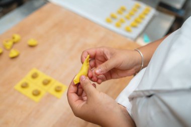 Ellerinizi dikkatlice katlayın. Taze tortellini makarna hamurunu ahşap bir masaya koyun.