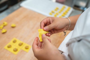 Taze makarna hamurunu dikkatlice katlayarak lezzetli dolgulu ev yapımı ravioli yapıyorlar.