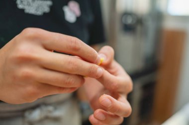 Makarna yapmak için ince bir sarı hamur telini dikkatlice şekillendiren eller.