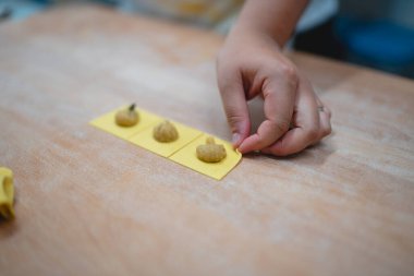 Küçük balkabağı şekilli mantıyı dikkatlice taze makarna hamuru karelerine yerleştirin.