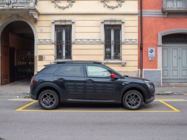 Cremona, İtalya 6 Şubat 2026 Citroen C4 Cactus SUV şehir caddesi boyunca açık bir şekilde işaretlenmiş sarı bir park alanına park edilmiş ve büyüleyici Avrupa mimarisi arka plan olarak hizmet vermektedir.