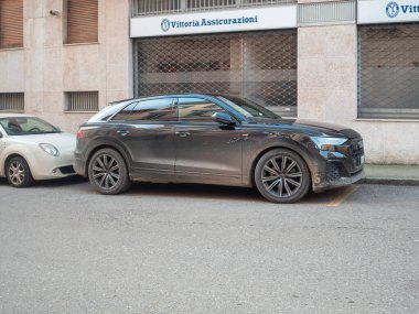 Cremona, İtalya 6 Şubat 2026 Black Audi Q8 S hattı çamura bulanmış, şehir sokağına park edilmiş ıslak toprak çizgili dış, tekerlek ve farları aydınlatan