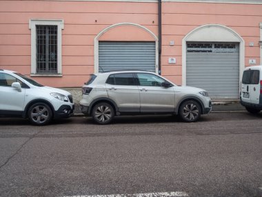 Cremona, İtalya 6 Şubat 2026 Beyaz Volkswagen T Cross SUV ve Opel Mokka kentsel bir caddeye park edilmiş küçük bir kavşak, modern ulaşımı gösteriyor